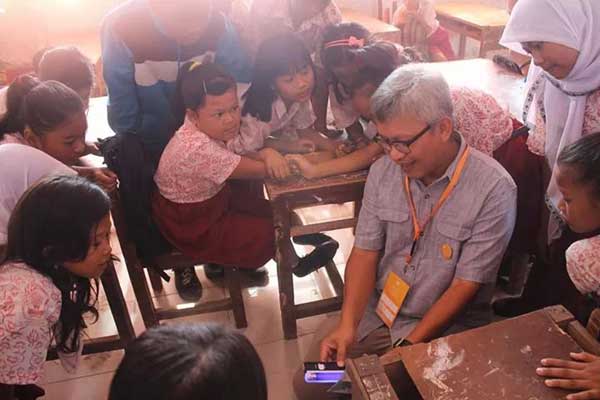 Difi A. Johansyah menunjukkan cara mendeteksi uang palsu dengan alat khusus kepada siswa-siswi SDN 065006 Kecamatan Medan Belawan